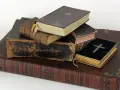 Stapel alter Bücher, einige mit Kreuzen auf dem Einband.