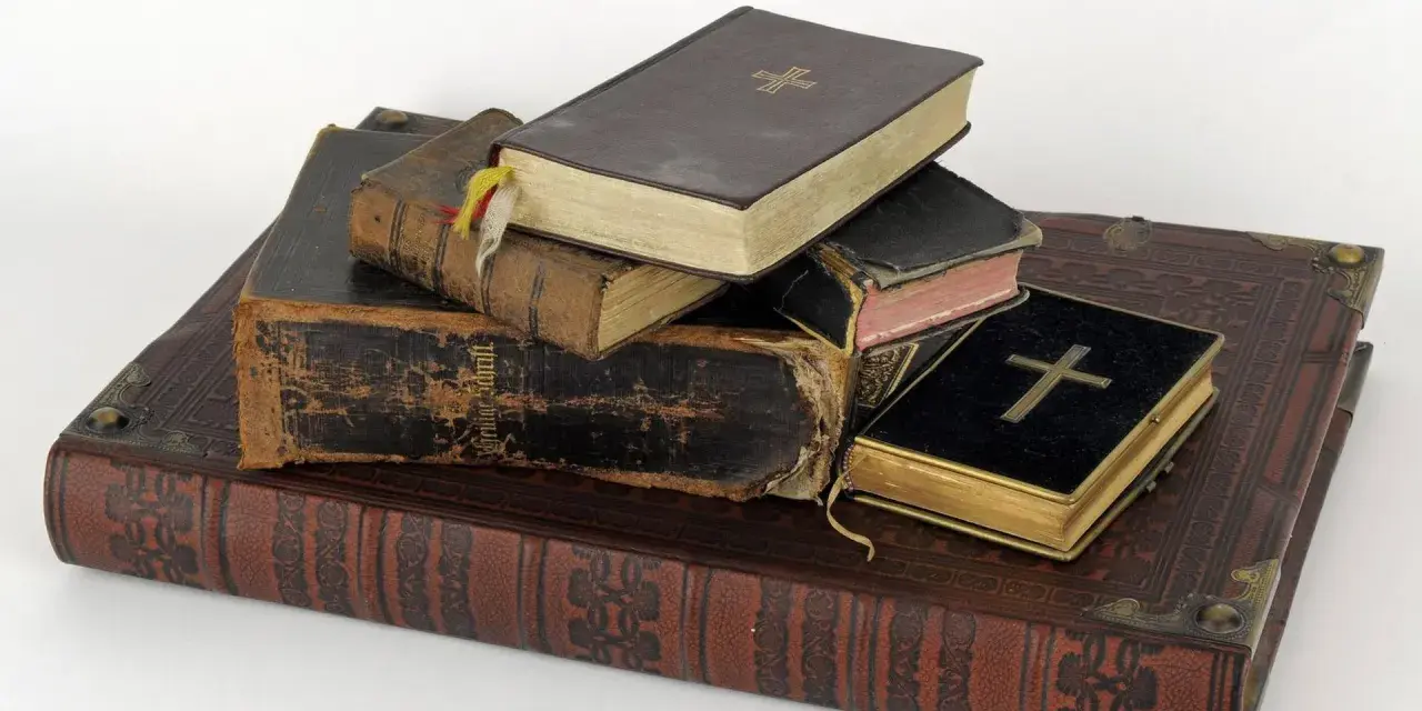 Stapel alter Bücher, einige mit Kreuzen auf dem Einband.